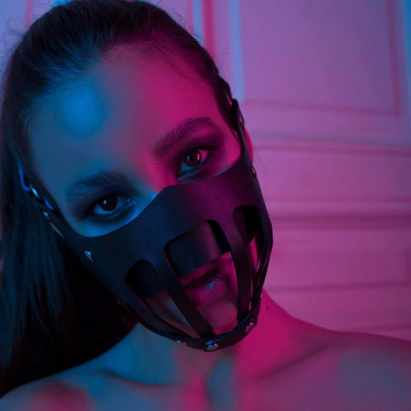 Close-up of a woman wearing a sexy leather face mask, featuring a unique design with vibrant lighting effects.