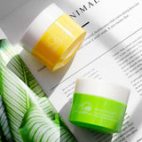 Meiqianer deep cleansing makeup remover cream jars in lemon and grapefruit, placed on a stylish magazine with green leaves.