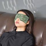 Relaxing woman wearing a green jade eye mask for facial lifting and massage benefits.